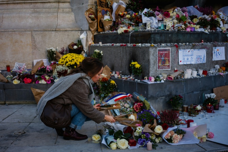 Une femme dépose des fleurs en hommage aux victimes du 13 novembre 2015, Place de la République à Paris, le 11 novembre 2025