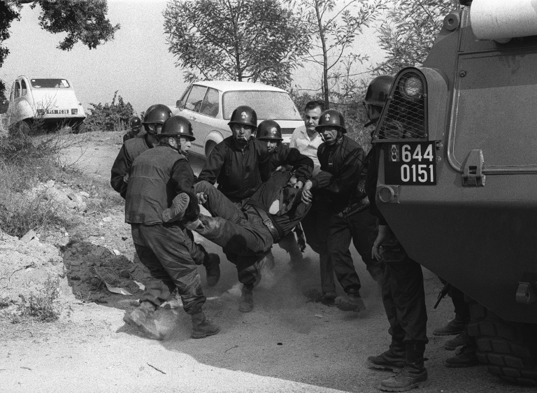 Des gendarmes évacuent un collègue blessé lors de leur intervention pour libérer six hommes pris en otage par des indépendantistes corses masqués et armés dans la cave à vin « Sovicor » à Aléria, en Corse, le 22 août 1975