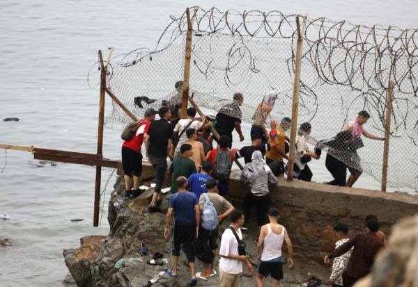 Des personnes sont rassemblées à côté d'une clôture près de Fnideq, à la frontière entre le Maroc et l'Espagne, le 31 juillet 2026