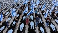 Des personnes brandissent des drapeaux israéliens alors qu'elles traversent une installation commémorative mise en place sur la plage de Tel-Aviv pour marquer le troisième anniversaire de l'attaque du Hamas contre Israël, le 7 octobre 2026