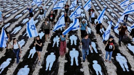 Des personnes brandissent des drapeaux israéliens alors qu'elles traversent une installation commémorative mise en place sur la plage de Tel-Aviv pour marquer le troisième anniversaire de l'attaque du Hamas contre Israël, le 7 octobre 2026