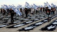 Des personnes portant des drapeaux israéliens traversent une installation commémorative sur la plage de Tel-Aviv pour marquer le troisième anniversaire de l'attaque du Hamas contre Israël, le 7 octobre 2026