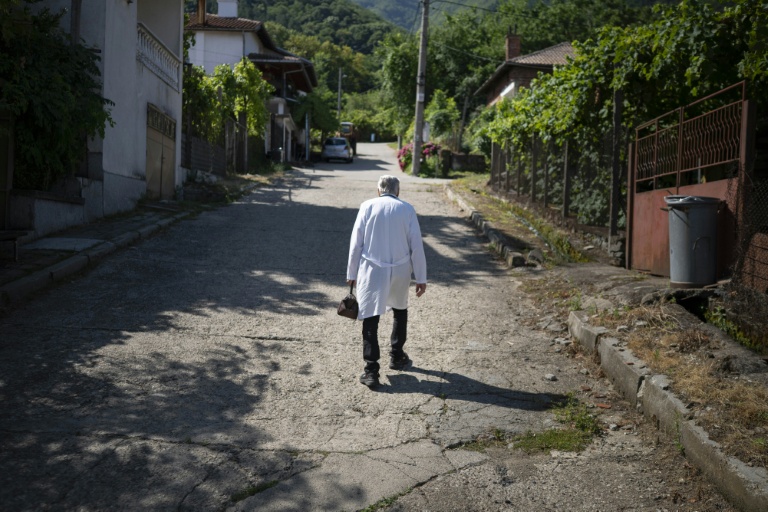 Le docteur Apostolov, médecin généraliste de 90 ans, gravit une rue escarpée de Skrat, un village situé au pied du massif de la Belassitsa en Bulgarie, le 15 juillet 2026