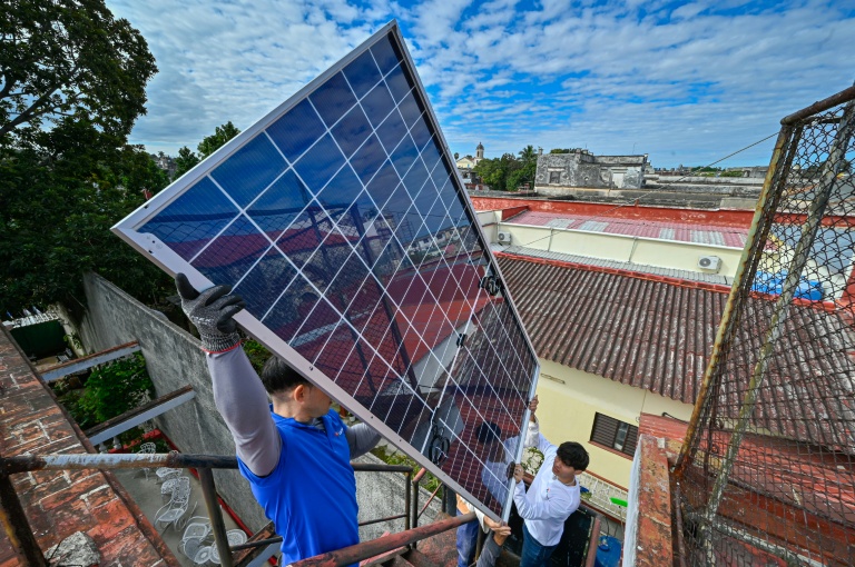Une équipe de techniciens de systèmes photovoltaïques hisse des panneaux sur le toit d'une cantine pour personnes âgées géré par l’Eglise catholique, dans le quartier de Guanabacoa à La Havane, le 4 février 2026