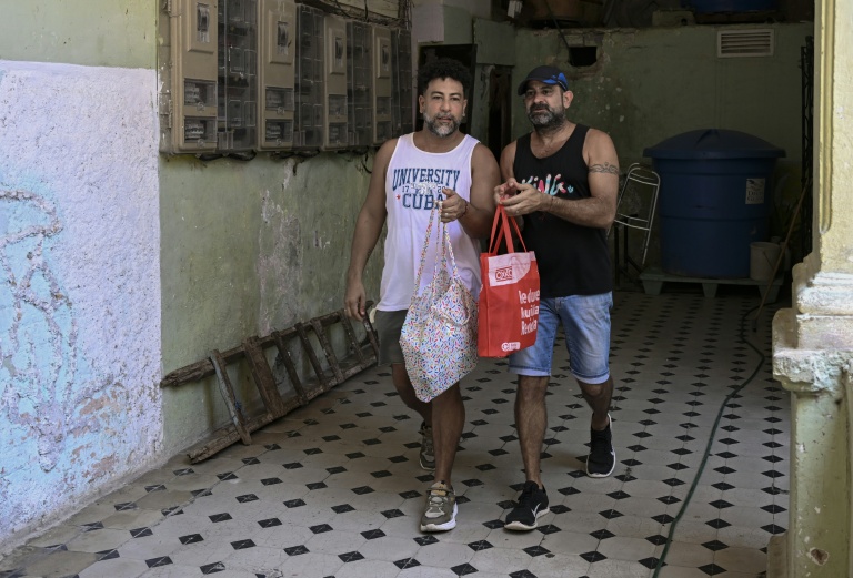 Leandro Wanton (à gauche) et Roberto Ronda, qui ont lancé un petit commerce de repas, vont livrer à pied une commande, le 31 juillet 2026 à La Havane