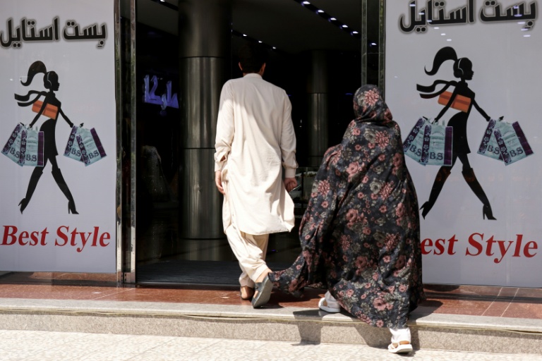 Un homme et une femme entrent dans un centre commercial, le 1er juillet 2026 à Hérat, dans l'ouest de l'Afghanistan 