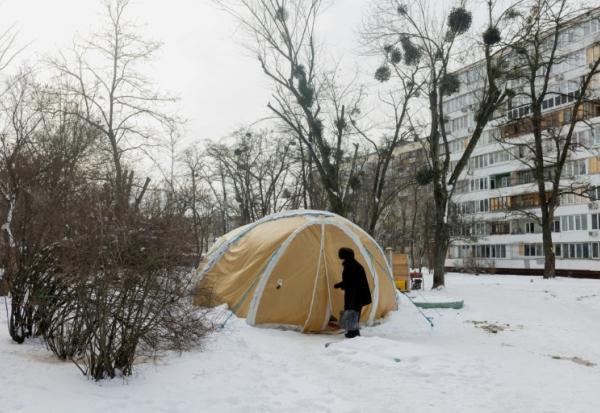 Une femme entre dans une tente proposant des services d'urgence, installée pour les personnes dont les logements sont privés d'électricité ou de chauffage, à Kiev, le 18 février 2026