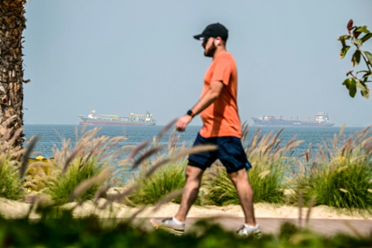 Un homme se promène sur le front de mer tandis que des cargos sont ancrés au large de Dubaï, le 2 mars 2026