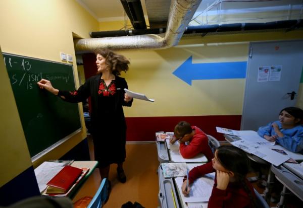 Des écoliers ont classe dans un abri installé au sous-sol de leur école primaire pendant une alerte aérienne en banlieue de Kiev, le 20 octobre 2026