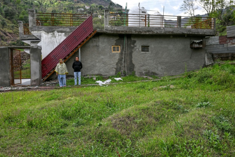 Rameez Khan (d) et son épouse Urusa Khan, qui ont perdu leurs jumeaux en fuyant lors du conflit indo-pakistanais de 2025, se tiennent près de leurs tombes devant leur maison dans le district frontalier de Poonch, le 6 avril 2026 en Inde