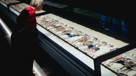 Une femme se penche pour observer la Tapisserie de Bayeux lors d'une avant-première réservée à la presse, organisée en amont de l'inauguration officielle au British Museum, dans le centre de Londres, le 7 septembre 2026