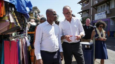 Édouard Philippe (c), fondateur et président du parti Horizons, maire du Havre et candidat à l'élection présidentielle, et Ambdilwahedou Soumaila (g), maire de Mamoudzou visitent une rue commerçante de Mamoudzou, le 21 août 2026 sur l'île de Mayottte