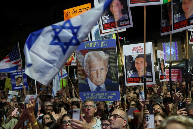 Des manifestants brandissent des drapeaux israéliens et américains, ainsi que des photos d'otages retenus à Gaza, lors d’un rassemblement à Tel-Aviv, le 11 octobre 2025