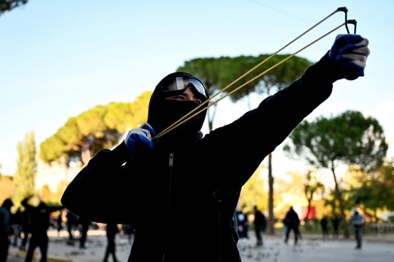 Un protestataire tire au lance-pierre sur les forces de police lors d'une manifestation antigouvernementale à Tirana, le 18 octobre 2026 en Alganie