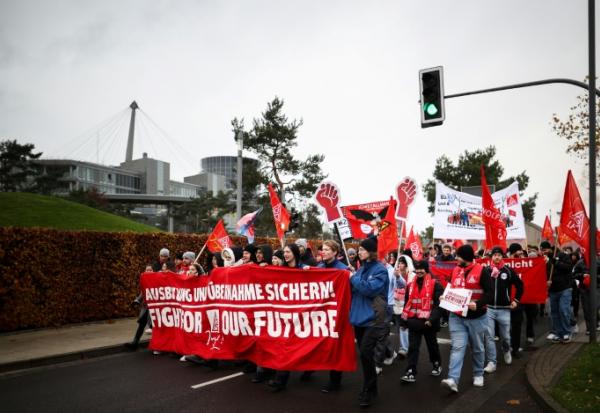 Des employés du constructeur automobile allemand Volkswagen déploient une banderole portant l'inscription "Fight for our Future" lors d'une manifestation à l'usine Volkswagen de Wolfsburg, dans le nord de l'Allemagne, le 21 novembre 2024