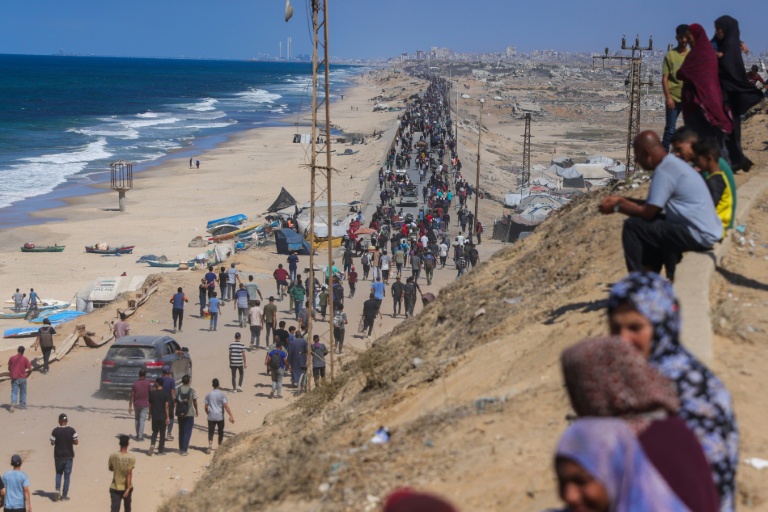 Des Palestiniens en marche sur la route al-Rachid en direction de la ville Gaza, après l'annonce du cessez-le-feu dans la bande de Gaza, le 10 octobre 2025.