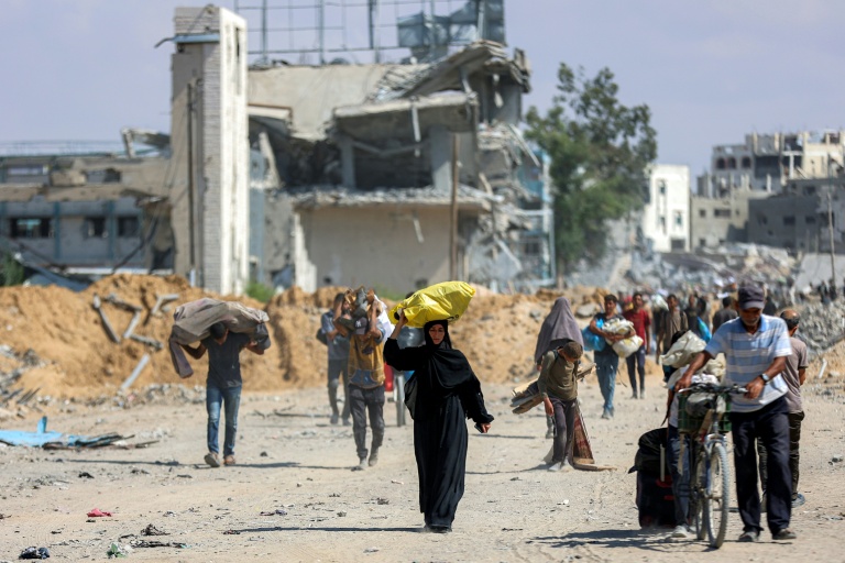 Des Palestiniens marchent sur une route dans le centre de Khan Younès, dans le sud de la bande de Gaza, le 10 octobre 2025.