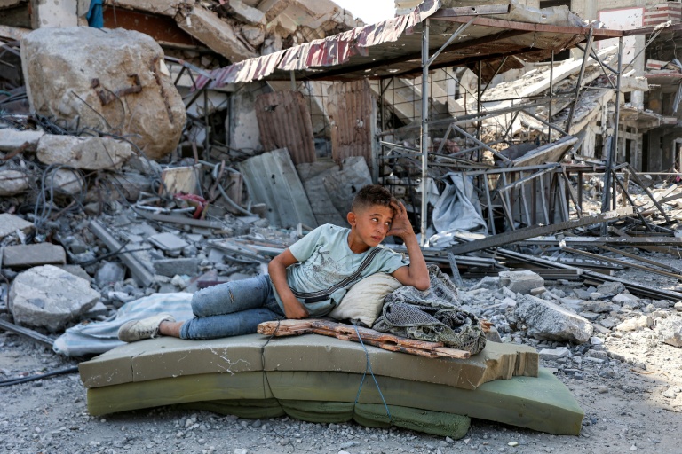 Un garçon palestinien se repose dans les décombres de Khan Younès, dans le sud de la bande de Gaza, le 10 octobre 2025.