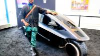 La star des Black Eyed Peas will.i.am pose devant Trinity, un tricycle électrique doté d'une IA, le 17 mars 2026 à San José aux Etats-Unis