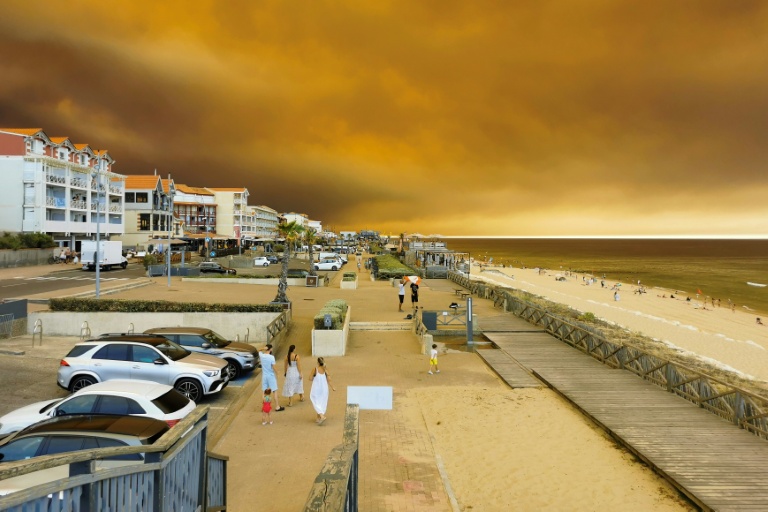 La plage à Lacanau-Océan, où la fumée d'un incendie de forêt s'élève dans le ciel, le 24 juillet 2026 en Gironde
