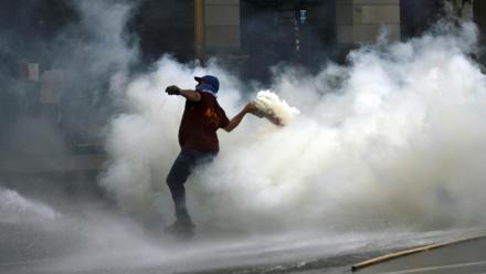 Un manifestant renvoie une grenade lacrymogène tirée par la police lors d'une manifestation devant le bâtiment du Parlement, où la réforme du travail du président argentin Javier Milei est examinée, à Buenos Aires, le 19 février 2026