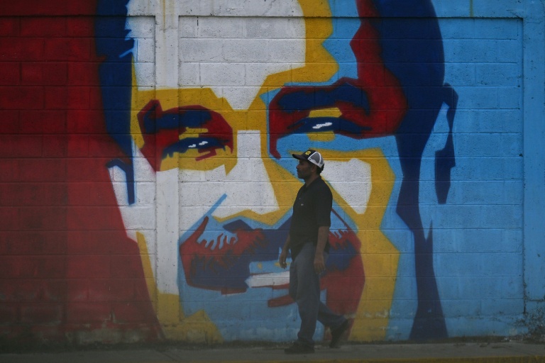 Un homme passe devant une fresque à l'effigie du président vénézuélien Nicolas Maduro, le 3 janvier 2026