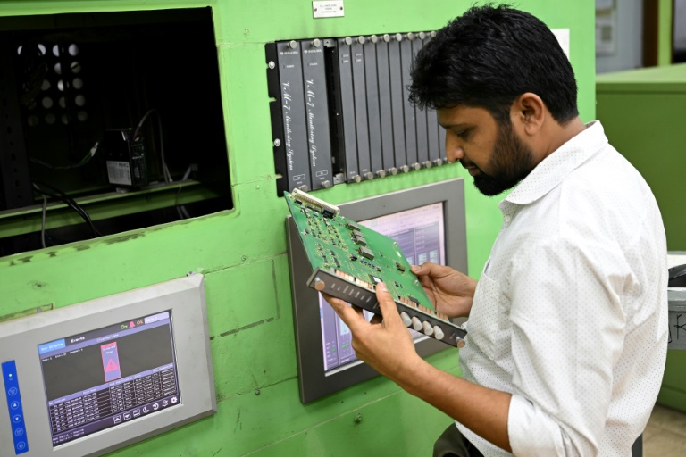 Un employé inspecte une plaque de circuits dans la salle de contrôle de l'usine d'engrais de Ashuganj, à l'arrêt depuis un an, le 12 août 2026 à Brahmanbaria, dans l'est du Bangladesh