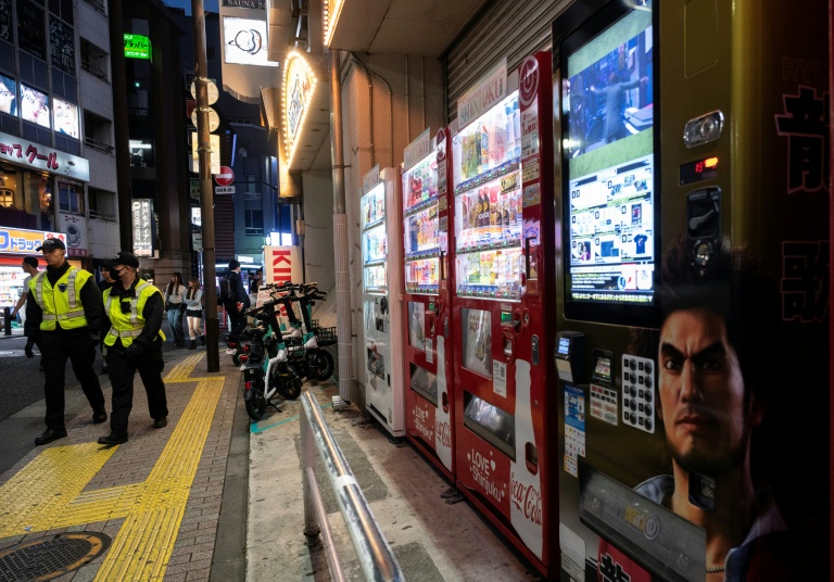 Des policiers passent près d'une rangée de  distributeurs automatiques, le 13 avril 2026 à Tokyo
