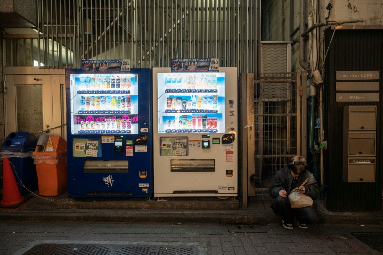 Un homme assis à côté de distributeurs automatiques, le 13 avril 2026 à Tokyo