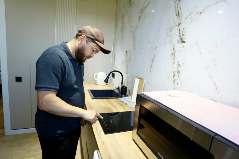 Erik Bekentaïev allume sa plaque à induction  dans son appartement à Chtchoutchinsk, le 27 mai 2026 au Kazakhstan