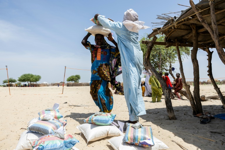 Une femme porte des sacs de maïs lors d'une distribution d'aide par le Comité international de la Croix-Rouge, dans un camp de déplacés à Kiskra, dans la province du lac Tchad, au Tchad, le 19 juin 2025