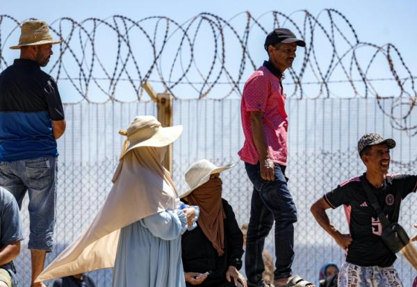 Des personnes attendent derrière une clôture surmontée de barbelés le retour de proches ayant tenté de franchir la frontière pour entrer dans l’enclave espagnole de Ceuta, le 2 août 2026 à Fnideq