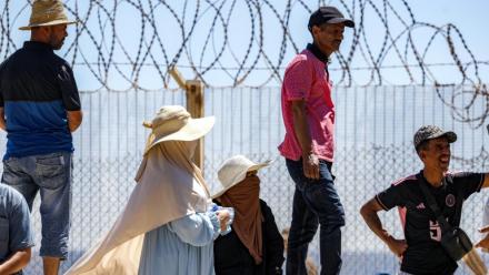 Des personnes attendent derrière une clôture surmontée de barbelés le retour de proches ayant tenté de franchir la frontière pour entrer dans l’enclave espagnole de Ceuta, le 2 août 2026 à Fnideq