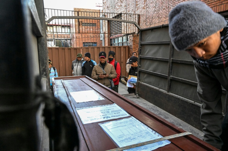 Lalit Bishowkarma (c) devant le cercueil contenant la dépouille de son père Rudra Bahadur Kami, le 21 janvier 2026 à l'aéroport de Katmandou, au Népal