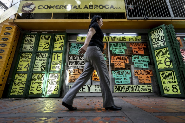 Une habitante passe devant des panneaux affichant des prix en dollars américains à Caracas, au Venezuela, le 2 juin 2025