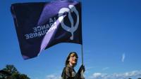 Une sympathisante de La France insoumise (LFI) tient un drapeau lors des universités d'été du parti (LFI), le 22 août 2026 à  Châteauneuf-sur-Isère, dans la Drôme 