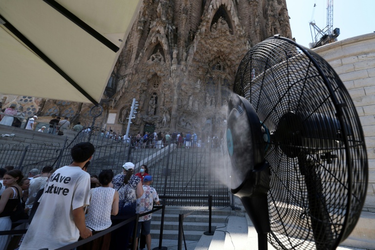 Un ventilateur brumisateur rafraîchit les touristes qui visitent la Sagrada Família à Barcelone, le 7 juillet 2026, lors d'une vague de chaleur en Espagne