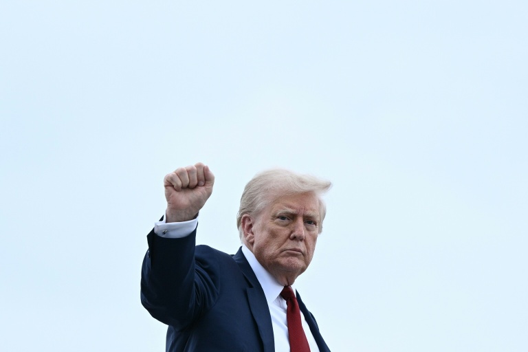 Le président américain Donald Trump lève le poing avant de monter à bord d'Air Force One, le 1er août 2025 à Base Andrews, dans le Maryland