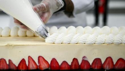 Un pâtissier travaille sur le plus grand fraisier du monde, d'une longueur de 121,88 m, à Argenteuil, le 23 avril 2025