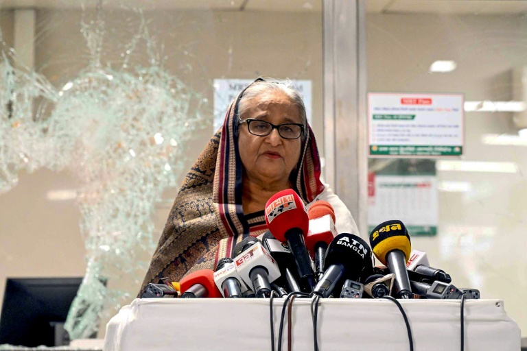 Sheikh Hasina s'adresse à des journalistes devant une station de métro vandalisée, dans la banlieue de Dacca, le 25 juillet 2024