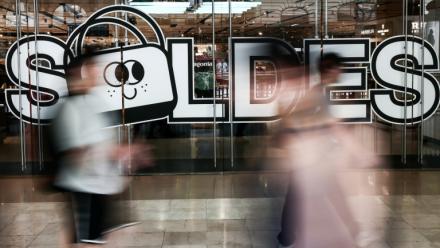 Des passants marchent à proximité de l'entrée d'un centre commercial annonçant les soldes, le 25 juin 2025 à Paris