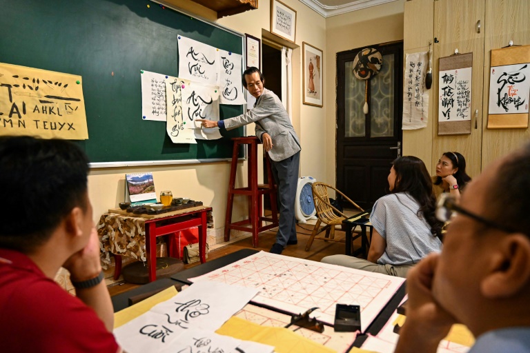 Le calligraphe Nguyen Thanh Tung (c) enseigne la calligraphie à des étudiants, chez lui à Hanoï, le 15 mai 2025 au Vietnam