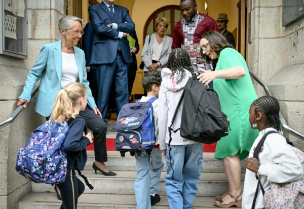 La ministre française de l'Éducation Elisabeth Borne (à gauche) accueille les élèves arrivant à l'école élémentaire publique Vigée-Lebrun le premier jour de classe après les vacances d'été, à Paris, le 1er septembre 2025