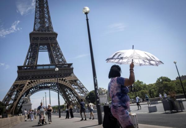 Une touriste se protège du soleil sous un parapluie, le 10 juillet 2026 à Paris 