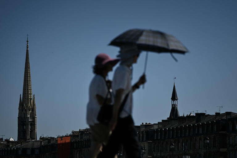 Des passants se protègent de la chaleur avec un parapluie, le 6 juillet 2026 à Bordeaux 