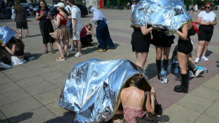 Des spectateurs se protègent de la chaleur  avec des couvertures de survie avant un concert de Bruo Mars à l'Olympic stadium de Berlin, le 28 juin 2026 en Allemagne