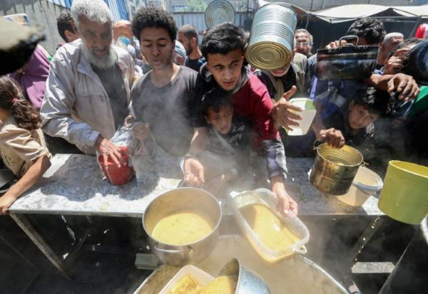 Des Palestiniens font la queue pour obtenir un repas chaud à une cuisine communautaire mise en place par le Programme alimentaire mondial (PAM), au camp de réfugiés de Nuseirat (Territoires palestiniens), dans le centre de la bande de Gaza, le 26 avril 2025