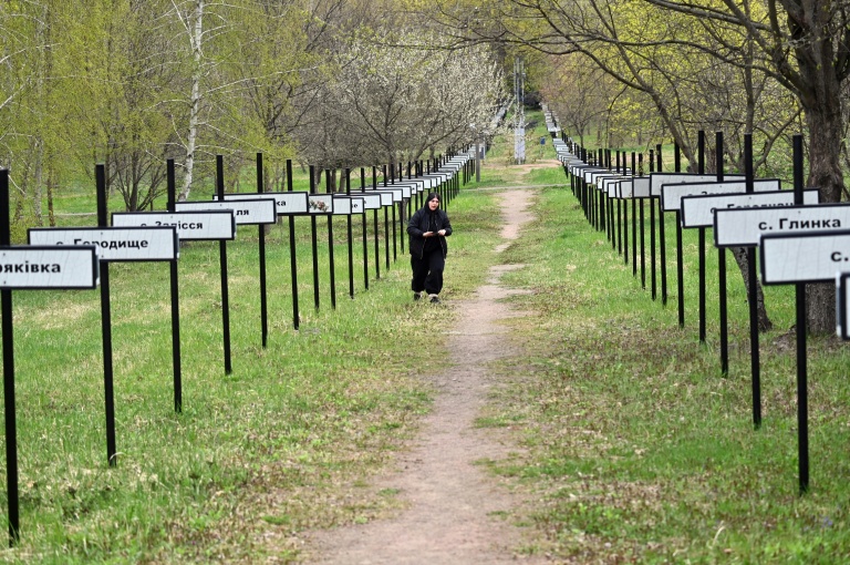 Une femme marche le 23 avril 2026 dans la ville de Tchernobyl, le long de l'allée commémorative portant les noms des villages disparus de la région
