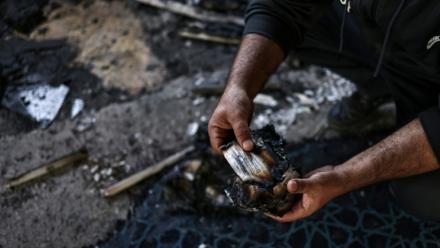 Un homme palestinien tient une page brûlée d'un Coran à l'intérieur de la mosquée Hajja Hamida à Dayr Istiya, dans le nord de la Cisjordanie occupée, le 13 novembre 2025, après une attaque présumée de colons juifs