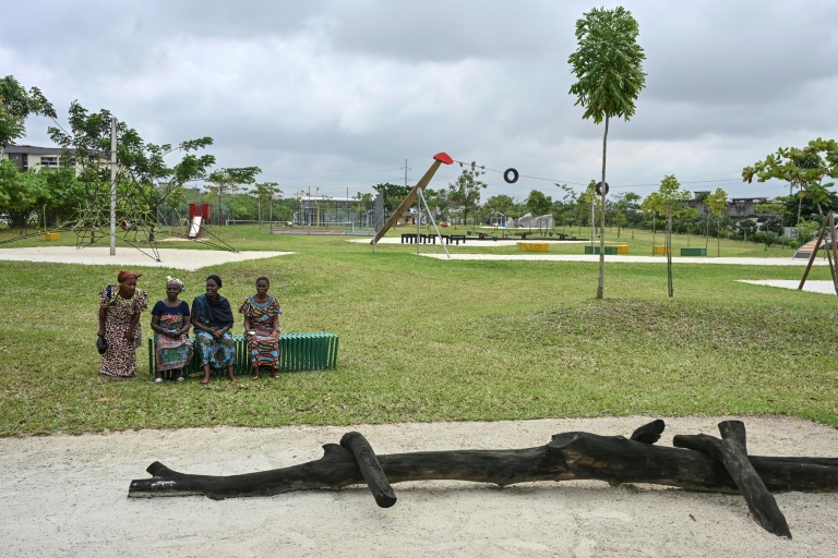 Des visiteurs sont assis, le 1er août 2025, sur un banc du parc urbain d'Akouédo, à Abidjan, construit sur le site d'une ancienne décharge